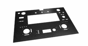 Retouched reference photograph of a CNC-cut carbon fiber panel with circular holes and rectangular cutouts.
